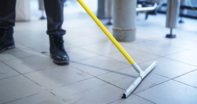 Close up of mop cleaning industrial plant floor.